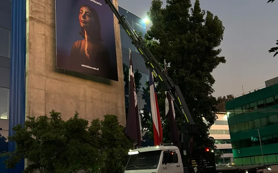Instalación de una gigantografía en altura mediante camión grúa, de noche